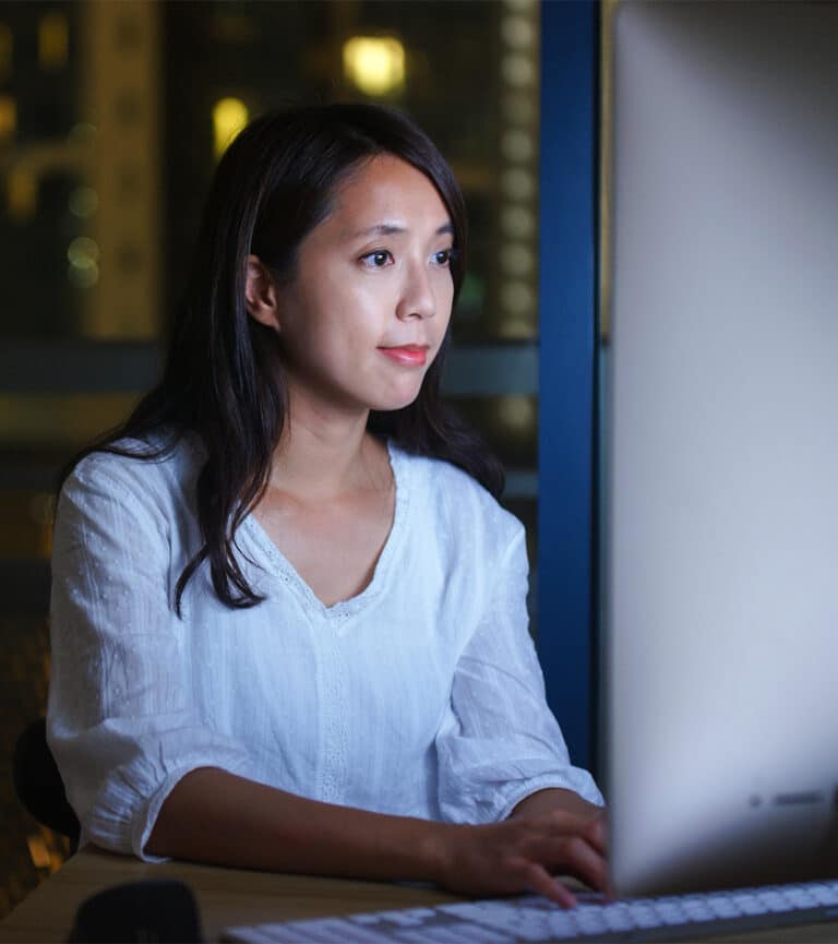Woman types on keyboard while looking at screen