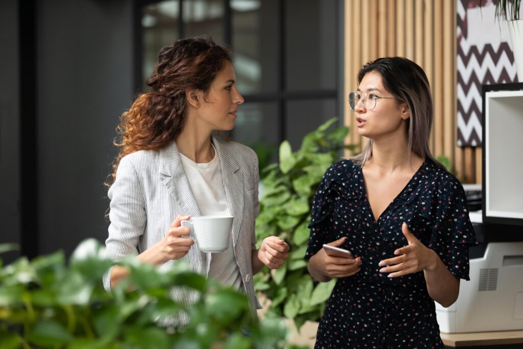 Two professional women walk side by side in an office.