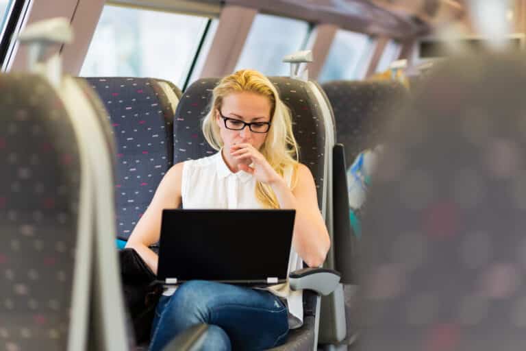 Businesswoman sitting and traveling by train working on laptop.