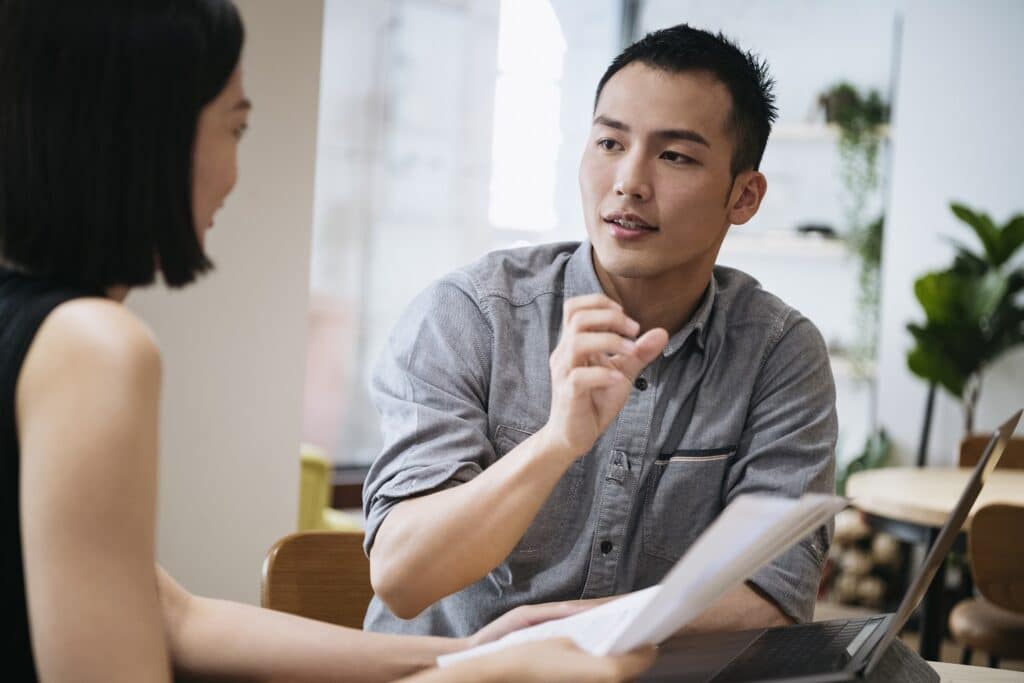 Young businessman gesturing to female coworker