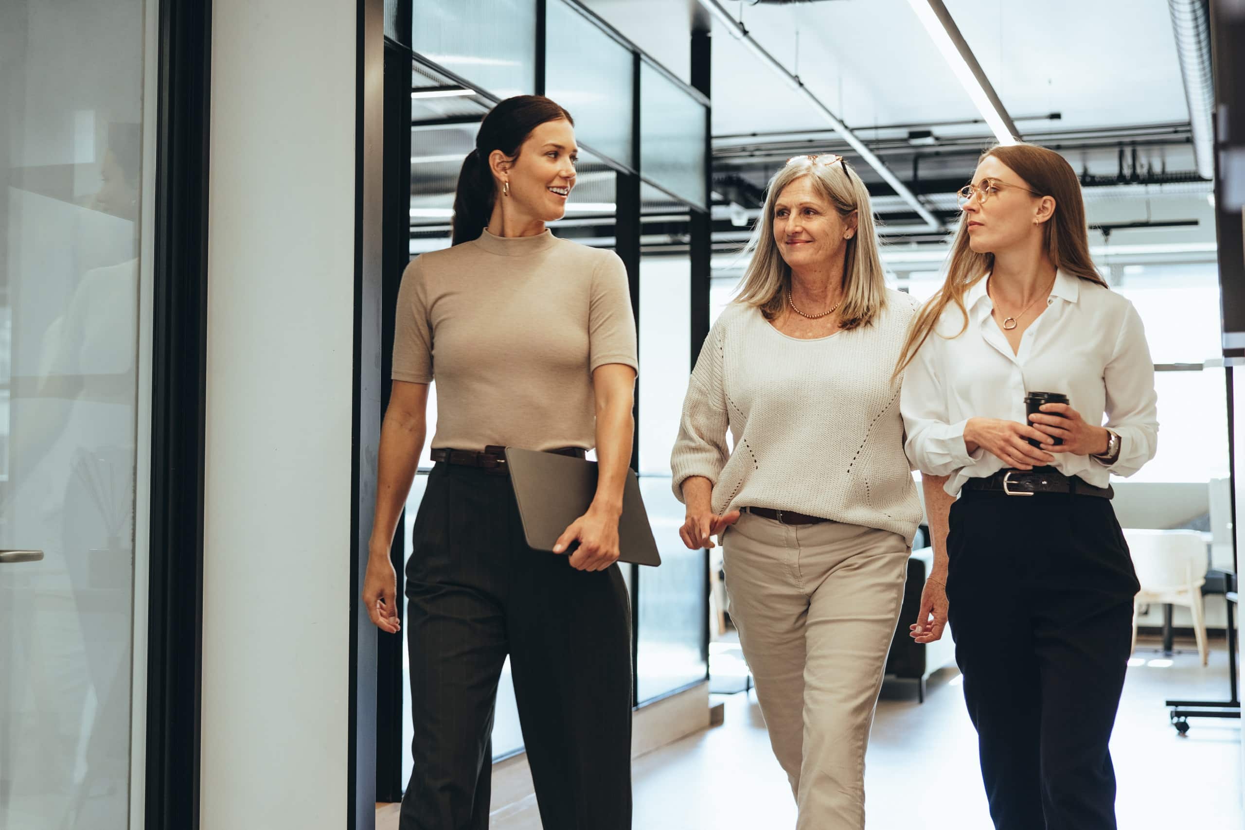 Three cheerful businesswomen walking together in an office. Diverse group of businesswomen smiling while having a discussion. Successful female colleagues collaborating on a new project.