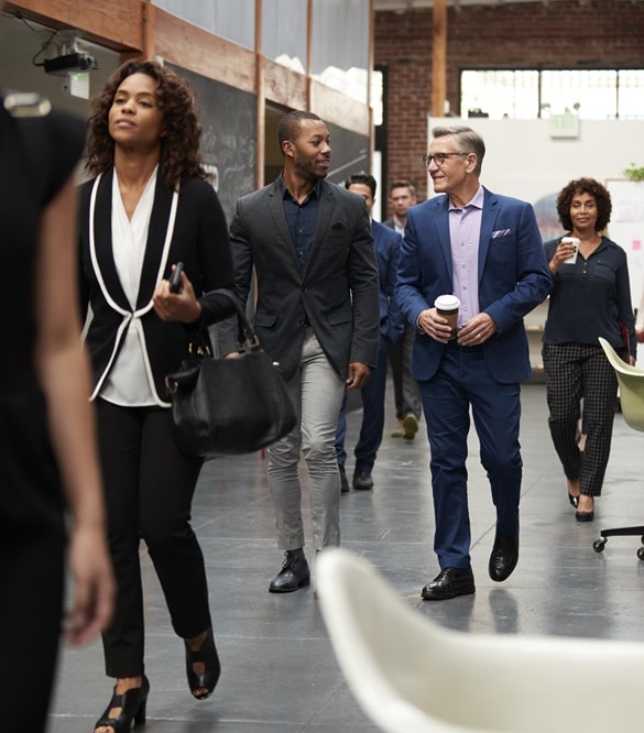 Businesspeople Arriving For Work In Busy Modern Open Plan Office