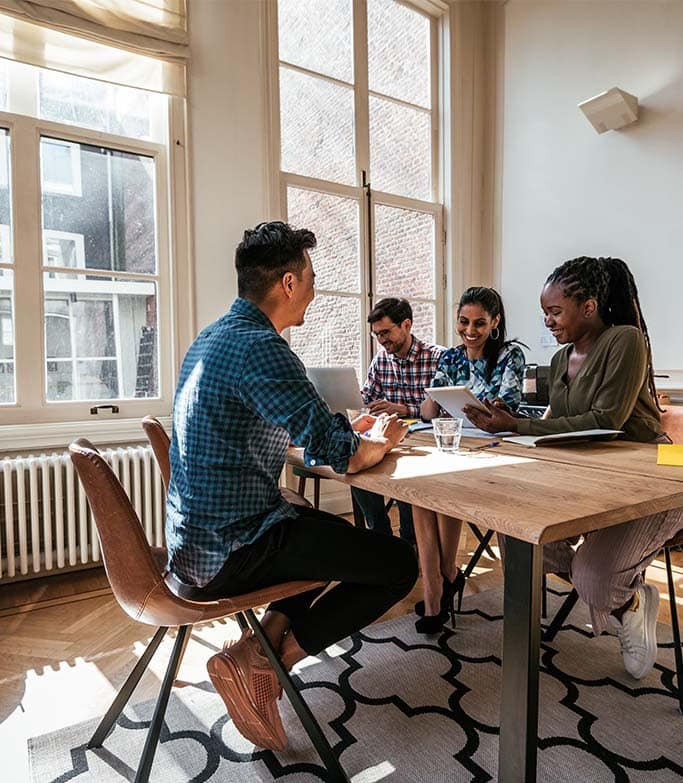 A group of colleagues sit around a table in an office