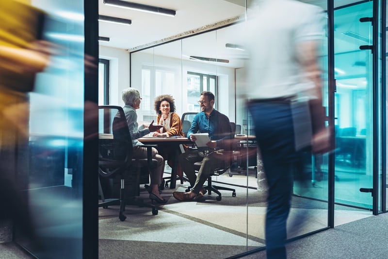 Group of business persons having a meeting in a closed glass conference room